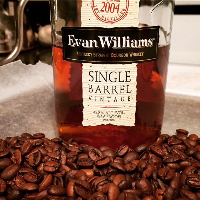 Freshly-roasted, bourbon-infused coffee on a cooling tray in front of a bottle of Evan Williams Single Barrel Bourbon