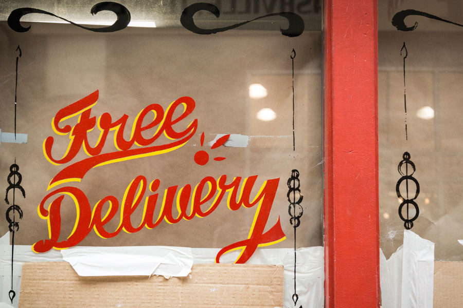 "Free Delivery" written in a script font on a restaurant window